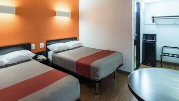 Habitación de hotel con dos camas, un escritorio, una silla y un microondas.