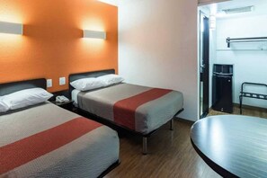 A hotel room with two beds, a desk, a chair, and a microwave.