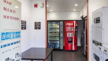 A hotel room with a minibar, a folding table, a Coca-Cola vending machine, and a water dispenser.