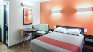 Een hotelkamer met een bed, een bureau, een stoel en een klein tafeltje.