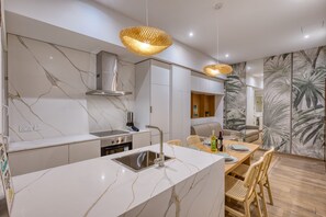 Una cocina moderna con encimera de mármol, electrodomésticos de acero inoxidable y un comedor con sillas de mimbre.