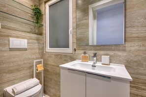 Ein Badezimmer mit Waschbecken, Spiegel, Handtuchhalter und Toilette.