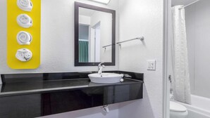 A bathroom with a white sink, black countertop, and a yellow towel rack. - 1 QUEEN BED | Nsmk, MINI FRIDGE (Riverside)