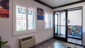 A reception area with a tiled floor, a wall-mounted air conditioner, and a glass door leading outside.