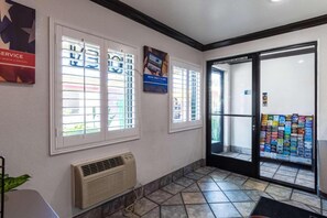 A reception area with a tiled floor, a wall-mounted air conditioner, and a glass door leading outside.
