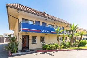 A building with a 'WELCOME' sign, a balcony, and a number '1260' on the facade. - 1 QUEEN BED | Nsmk, MINI FRIDGE (Riverside)