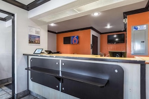 Ein Hotel-Rezeptionsbereich mit einer Theke, einer digitalen Anzeige und einem Schild, das Zimmer Nummer 6 anzeigt.