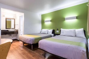 Habitación de hotel con dos camas, un escritorio y un espejo.
