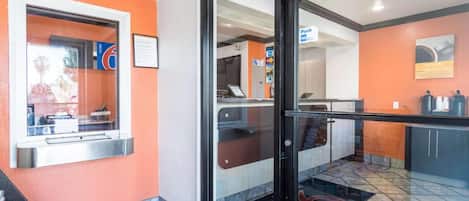 A modern interior with a reception desk, a coffee machine, and a counter with a menu.