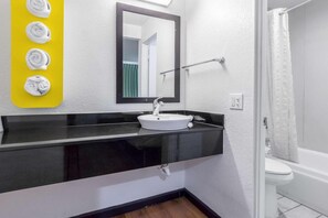 Ein Badezimmer mit einem weißen Waschbecken, einer schwarzen Arbeitsplatte und einem gelben Handtuchhalter.