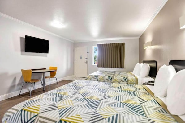 Une chambre d’hôtel équipée d’un lit, d’un bureau, d’une chaise et d’un téléviseur.