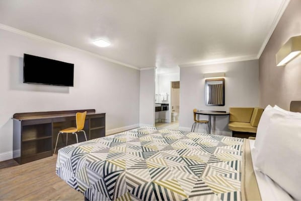 Une chambre d’hôtel équipée d’un lit, d’un bureau, d’une chaise, d’une télévision et d’un miroir.