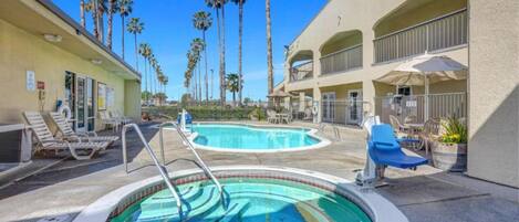 A pool area with lounge chairs and a hot tub.