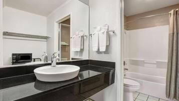 A modern bathroom with a black countertop, white sink, and a shower area.