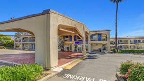 A hotel with a covered entrance, a parking area, and a palm tree in the background. - 2 Queen Beds|ADA/RI Shower/Non-Smoking (Lodi)