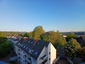 A residential area with multi-story buildings, a clear sky, and a tree in the foreground.