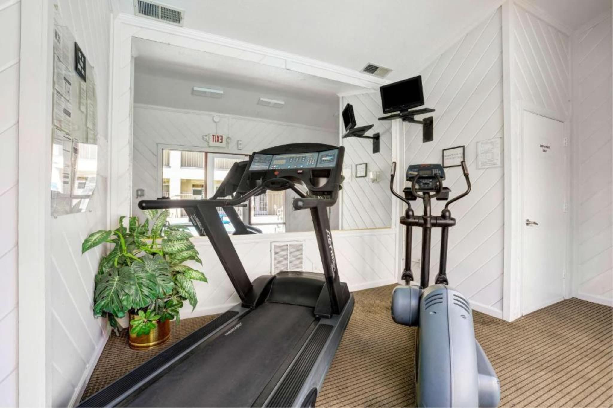 Gimnasio con cinta de correr, elíptica y bicicleta estática.