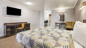 Una habitación de hotel con cama, escritorio, silla, televisión y un baño a la vista.