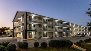 A multi-story motel with a central office, multiple balconies, and a parking area. - 1 queen bed | kitchen non-smoking (Savannah GA)