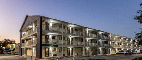A multi-story motel with a central office, multiple balconies, and a parking area.