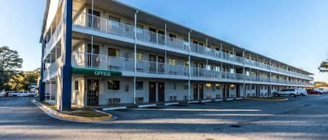 A multi-story motel with a green 'OFFICE' sign, multiple balconies, and a parking lot.