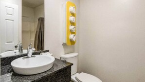 A bathroom with a sink, mirror, toilet, and a towel dispenser. - 1 queen bed | kitchen non-smoking (Savannah GA)
