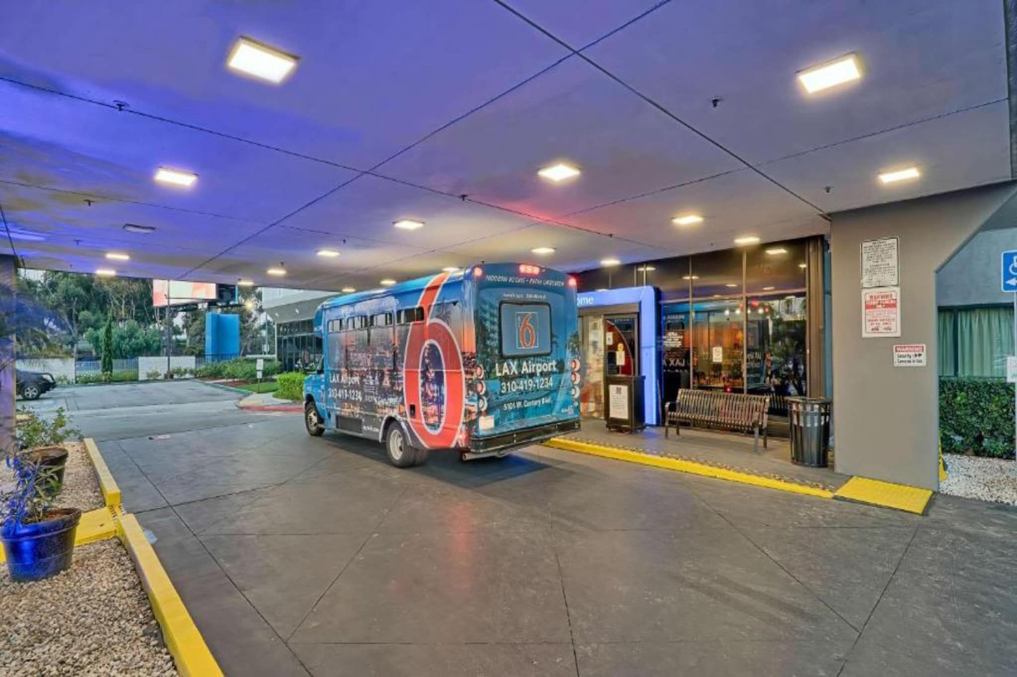 A bus parked at a bus stop with a sign for LAX Airport.
