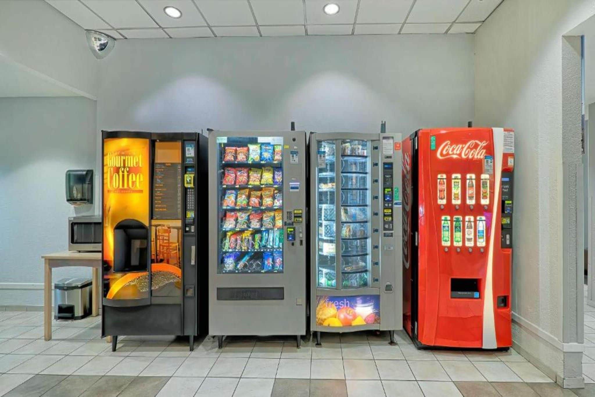 A row of vending machines including a coffee machine, snack dispensers, and a Coca-Cola machine.