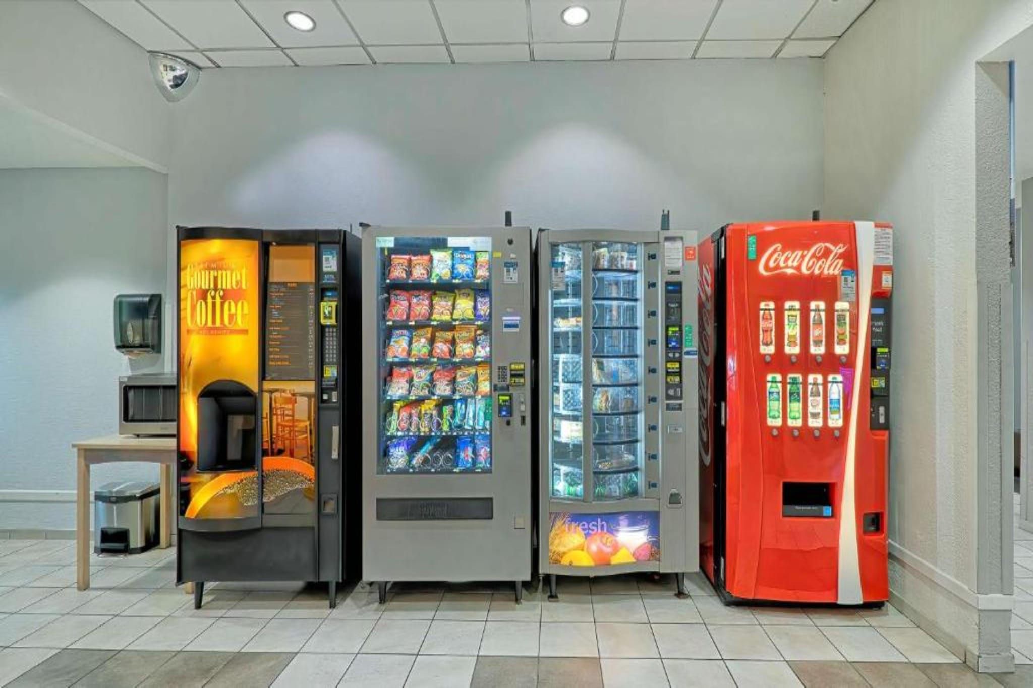 A row of vending machines including a coffee machine, snack dispensers, and a Coca-Cola machine.