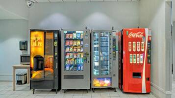 A row of vending machines including a coffee machine, snack dispensers, and a Coca-Cola machine.