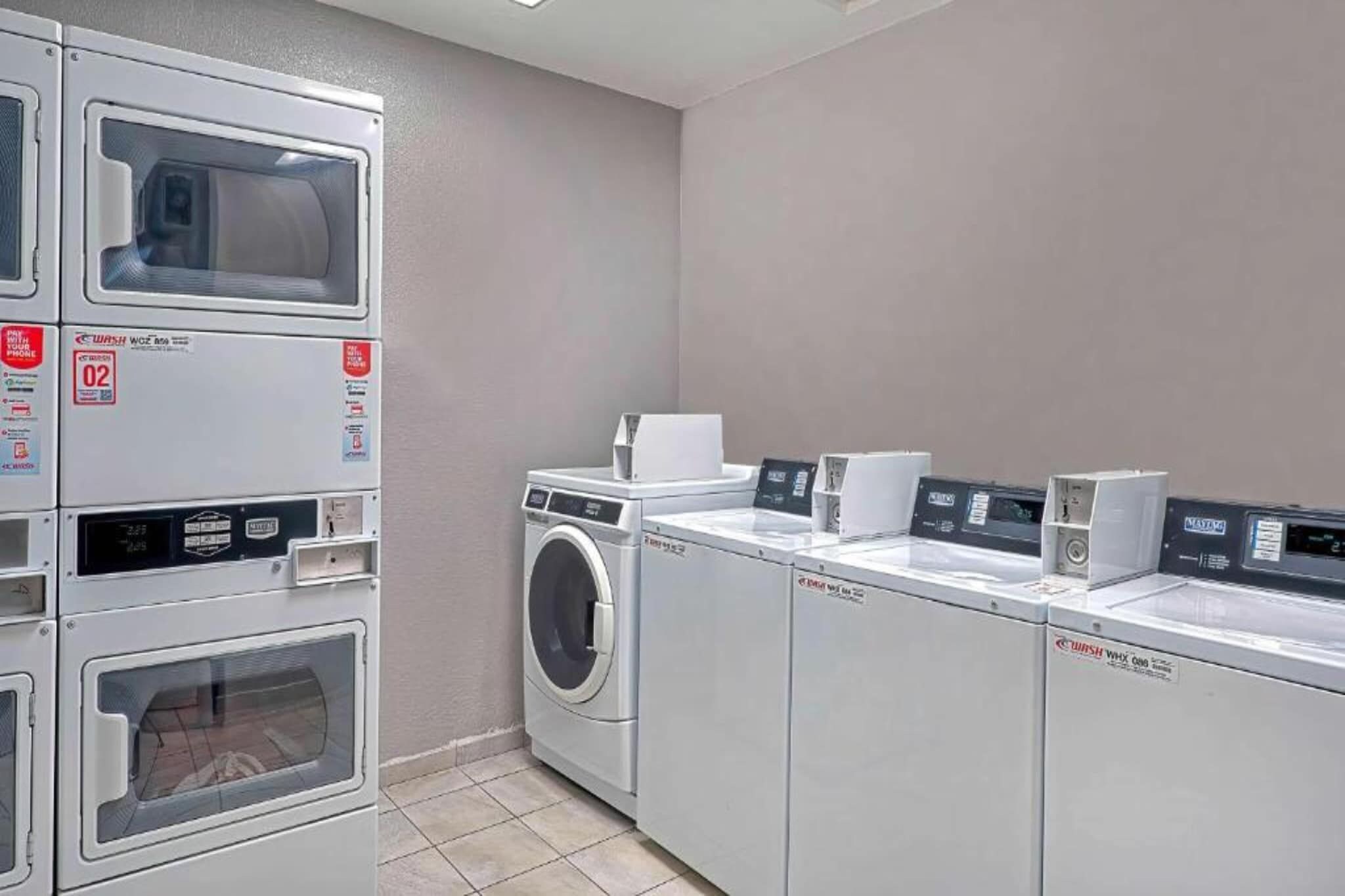 Een wasserette met gestapelde wasmachines en drogers, inclusief een wasmachine en een droger.