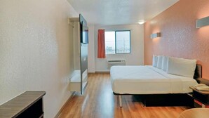 Una camera d'albergo con un letto, una scrivania, una sedia, una finestra e un riscaldatore a parete.