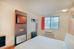 A hotel room with a bed, a television mounted on the wall, a window with curtains, and an air conditioning unit. - 1 King Bed|Suite,Nsmk,Micfridge (Inglewood)