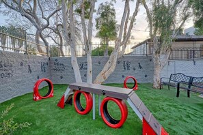 A playground with a seesaw and tire swings, surrounded by a stone wall with graffiti. - 1 King Bed|Suite,Nsmk,Micfridge (Inglewood)