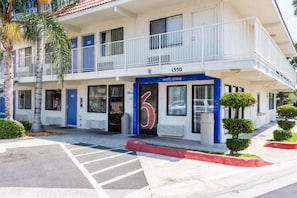 A two-story motel with a '6' sign, a balcony, and a 'welcome' sign. - Cozy Queen Bed Room|Pool|Free Wifi (Bakersfield)