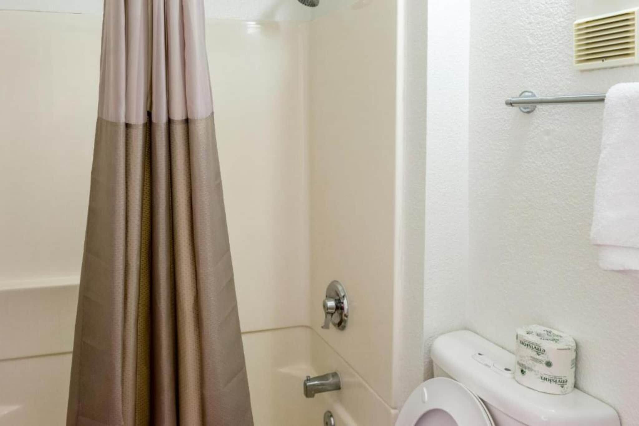 A bathroom with a shower curtain, a toilet, and a towel rack.