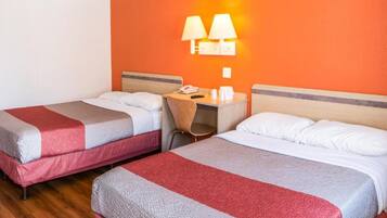 A hotel room with two beds, a desk, and a chair.