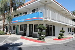 A two-story building with a blue 'WELCOME' sign, a covered entrance, and a small tree in the front yard.