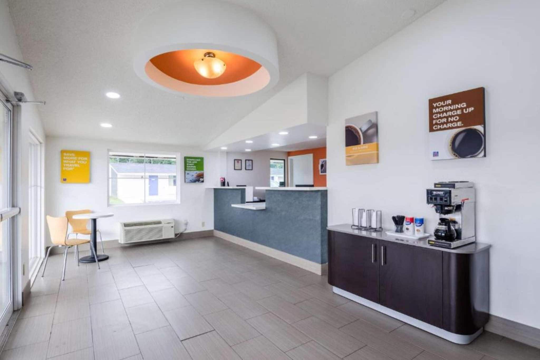 A modern reception area with a counter, seating, and a coffee machine.