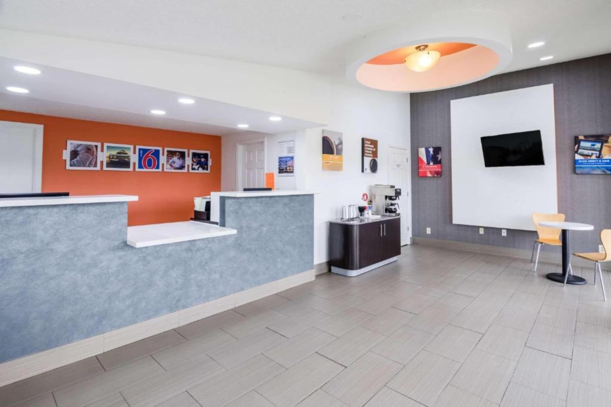 A reception area with a counter, seating, a coffee machine, and a TV on the wall.
