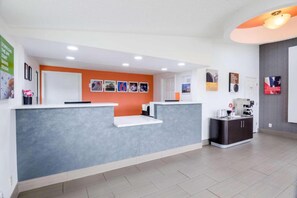 A reception area with a grey reception desk, a white counter, and a wall with framed pictures. - 2 FULL BEDS | NON-SMOKING, MICFRIDGE (Troutville)