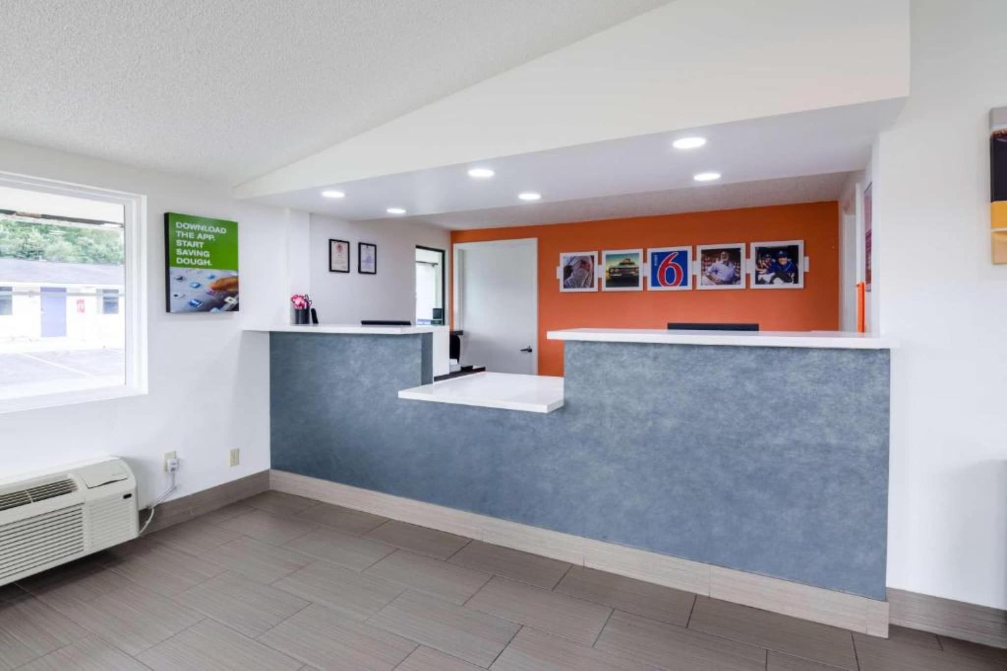 Un área de recepción con mostrador, cuadros en la pared y una ventana con vistas al exterior.