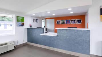 Un área de recepción con mostrador, cuadros en la pared y una ventana con vistas al exterior.
