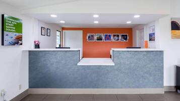 A reception area with a grey reception desk, a white counter, and a wall with framed pictures.