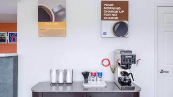 A coffee station with a coffee machine, cups, and a sign promoting a no-charge morning charge.