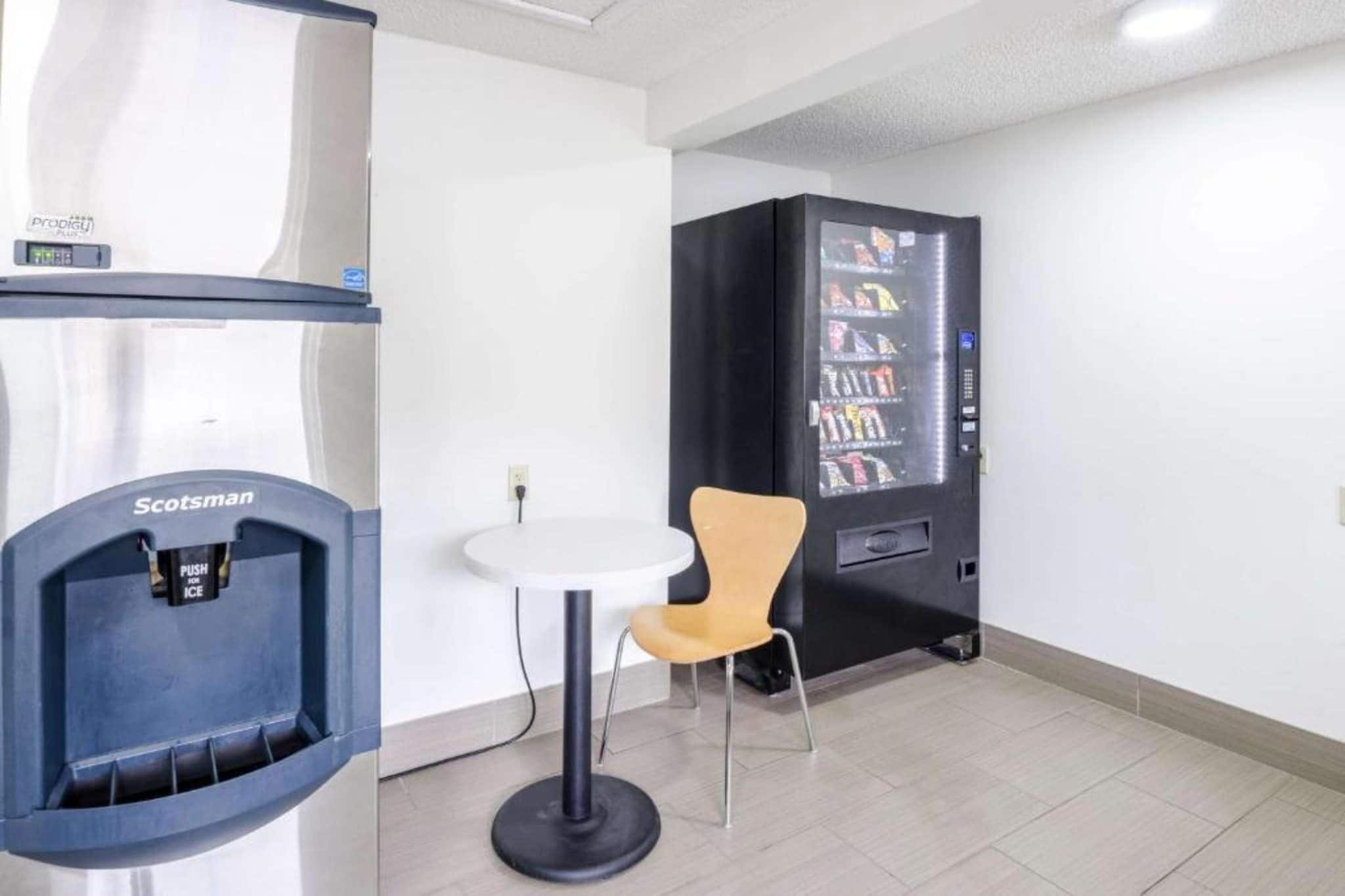 Quarto com máquina de vendas, mesa e cadeira.