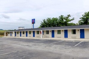 Un motel composé d’une rangée de chambres individuelles, d’un parking et d’une enseigne bleue indiquant le nombre de chambres.