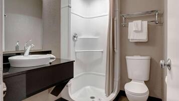A modern bathroom with a shower, toilet, sink, and a mirror.