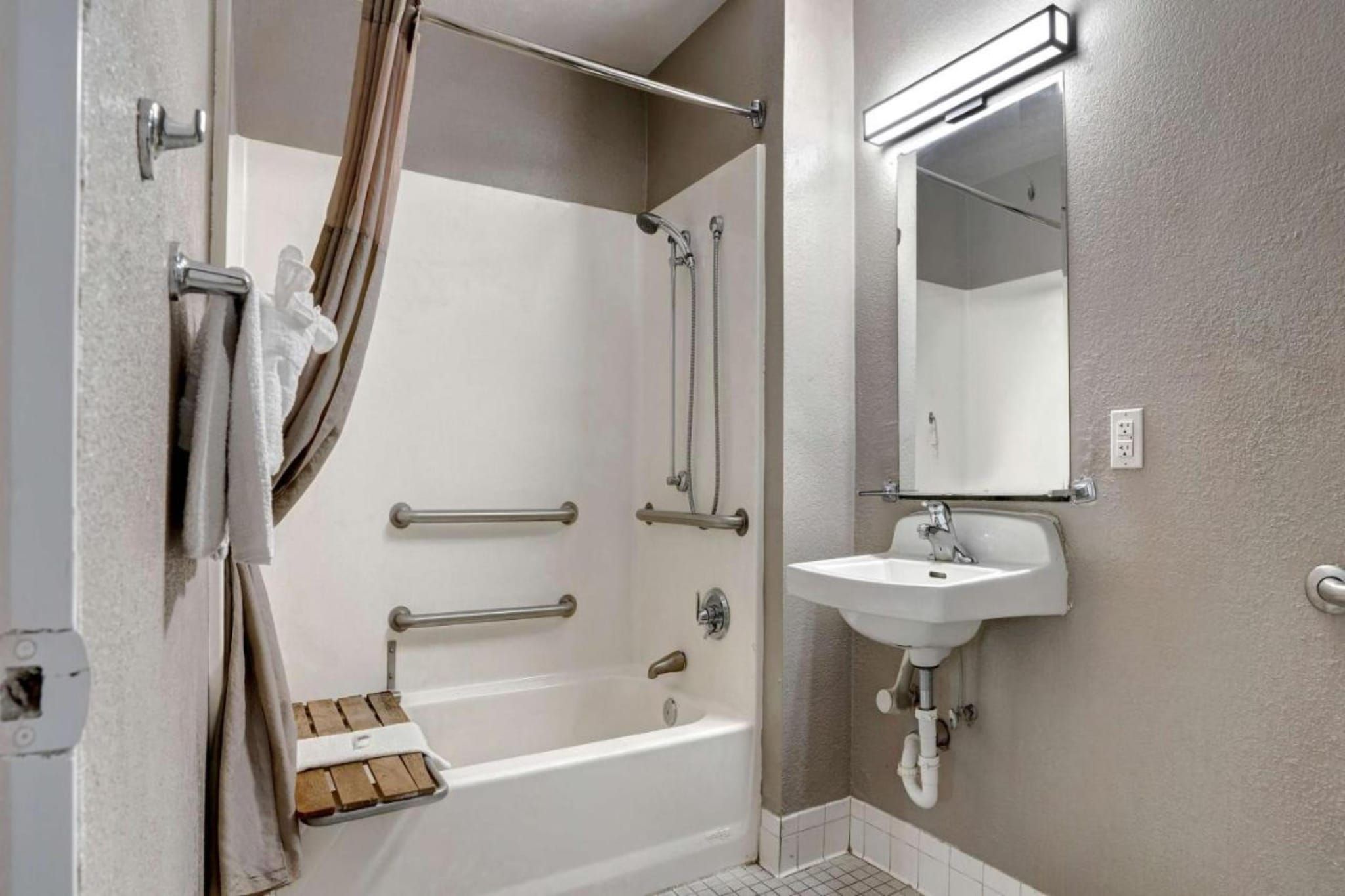 A bathroom with a bathtub, a shower, a sink, and a mirror.