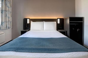 A hotel room with a bed, two bedside tables, a wardrobe, and a curtain with a leaf pattern. - 1 Full Bed | ADA/RI Shower (Bakersfield)